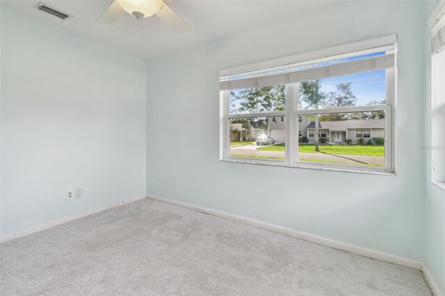 carpeted empty room featuring ceiling fan and a wealth of natural light