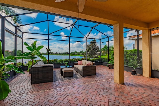 view of patio / terrace featuring ceiling fan, a water view, an outdoor hangout area, and glass enclosure