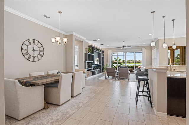 dining space featuring ceiling fan with notable chandelier, crown molding, and sink