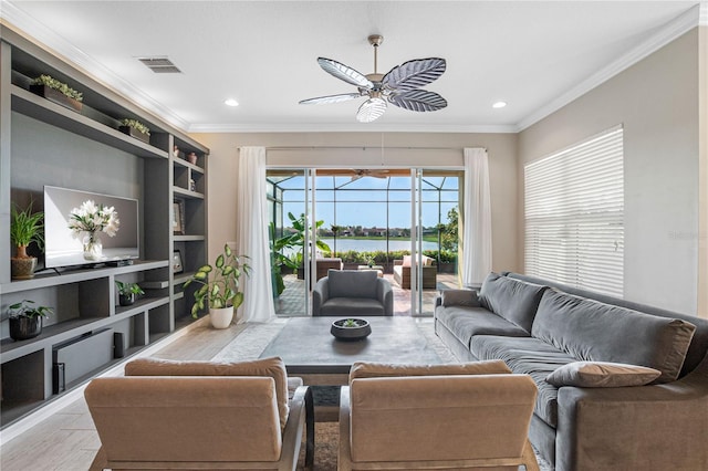 living room featuring ceiling fan, a water view, and crown molding