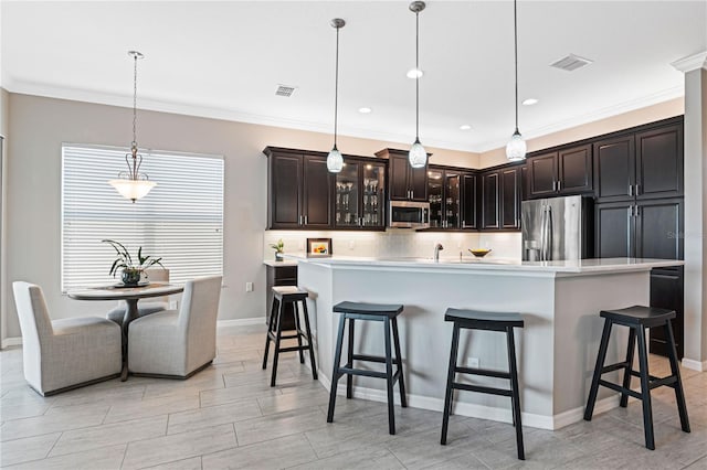 kitchen featuring dark brown cabinetry, a large island with sink, pendant lighting, a kitchen bar, and appliances with stainless steel finishes