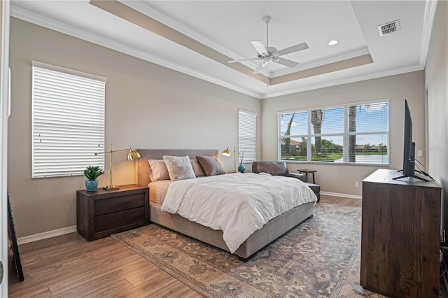 bedroom featuring a raised ceiling, ceiling fan, crown molding, and wood-type flooring