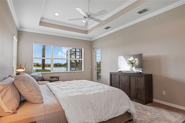 bedroom with a tray ceiling, light hardwood / wood-style flooring, ceiling fan, and ornamental molding