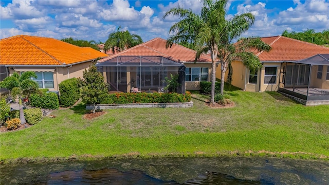 back of house featuring a lawn, a lanai, and a water view