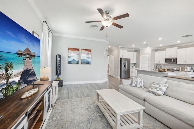 living room featuring light hardwood / wood-style flooring, ceiling fan, and crown molding