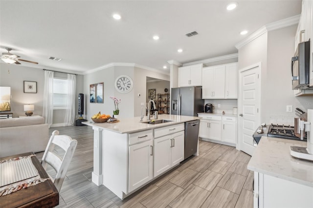 kitchen featuring white cabinetry, appliances with stainless steel finishes, a kitchen island with sink, and sink