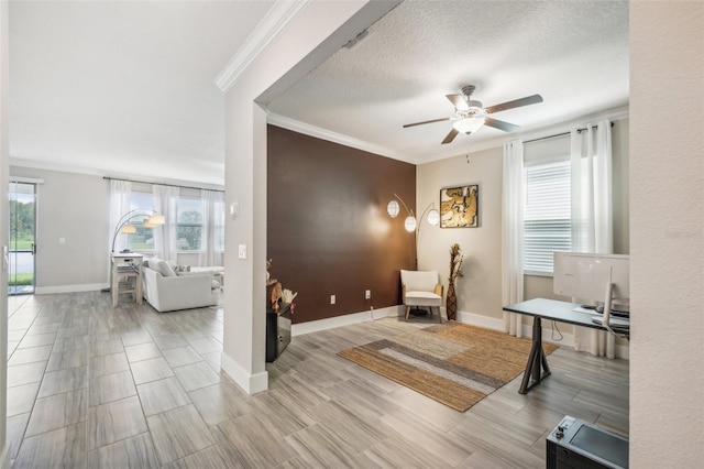 living area featuring a textured ceiling, light hardwood / wood-style floors, ornamental molding, and ceiling fan