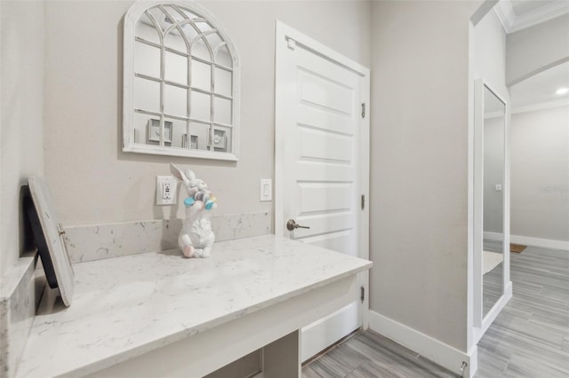 interior space featuring ornamental molding, light wood-type flooring, and light stone counters