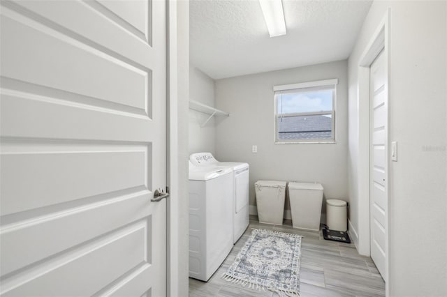 clothes washing area with a textured ceiling, light wood-type flooring, and washing machine and clothes dryer