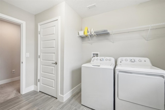 clothes washing area featuring light hardwood / wood-style floors and separate washer and dryer