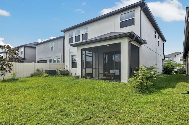 back of house featuring central AC unit, a sunroom, and a lawn