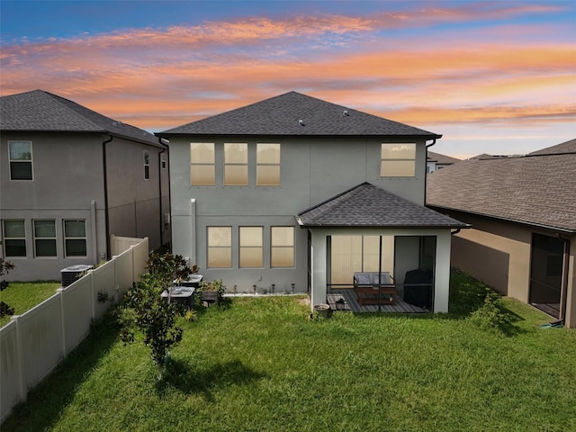 back house at dusk featuring a yard