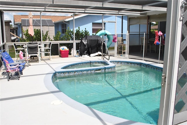 view of swimming pool featuring a patio, glass enclosure, and an in ground hot tub