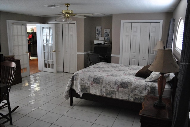 tiled bedroom with two closets and ceiling fan