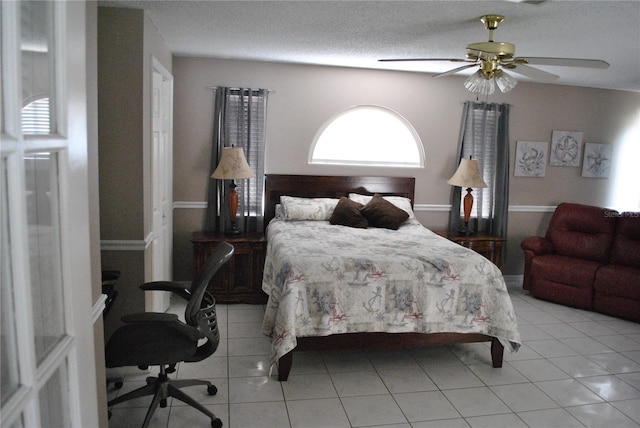 bedroom featuring ceiling fan, light tile patterned flooring, and a textured ceiling