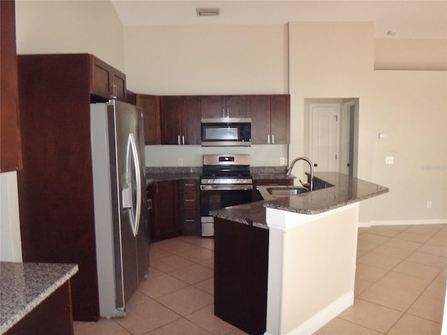 kitchen featuring dark brown cabinets, light tile patterned floors, appliances with stainless steel finishes, and sink