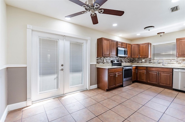 kitchen with backsplash, light tile patterned floors, stainless steel appliances, ceiling fan, and sink