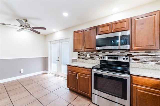 kitchen with light tile patterned floors, ceiling fan, stainless steel appliances, and light stone counters