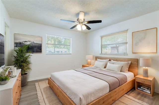 bedroom featuring multiple windows, light hardwood / wood-style floors, and ceiling fan