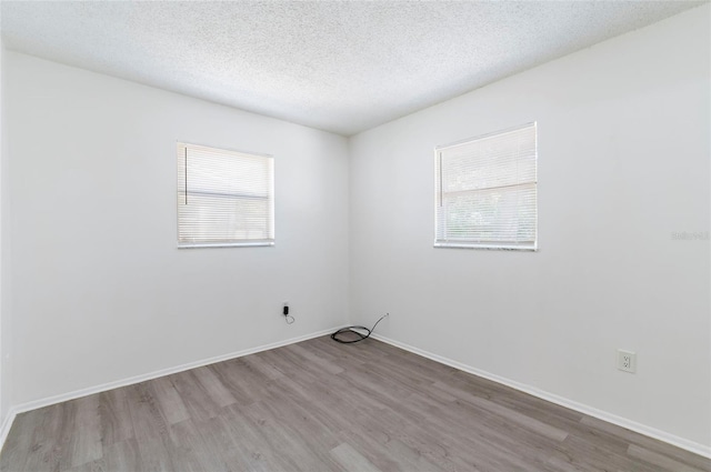 empty room featuring a textured ceiling and light hardwood / wood-style floors