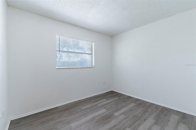 empty room featuring a textured ceiling and wood-type flooring