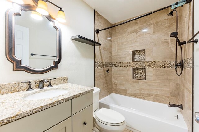 full bathroom featuring vanity, tiled shower / bath combo, and toilet