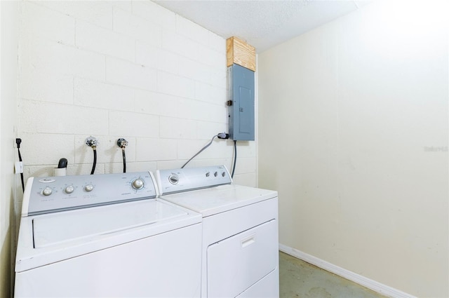 laundry room featuring a textured ceiling, washer and clothes dryer, and electric panel