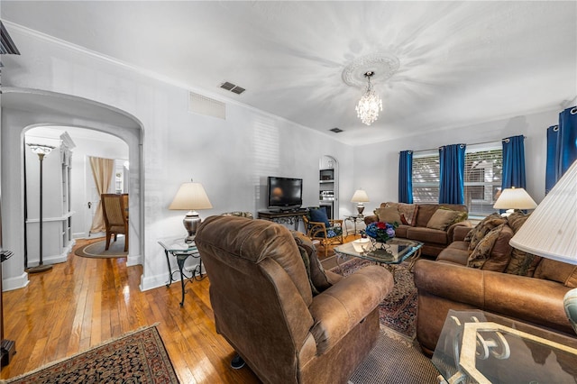 living room featuring wood-type flooring, an inviting chandelier, and ornamental molding