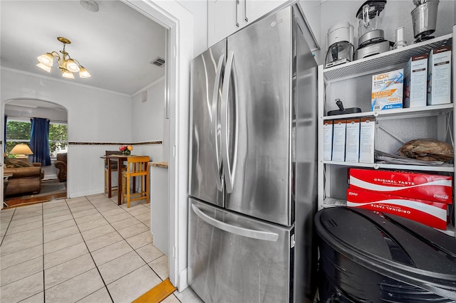 kitchen featuring stainless steel fridge, white cabinets, light tile patterned floors, ornamental molding, and a chandelier