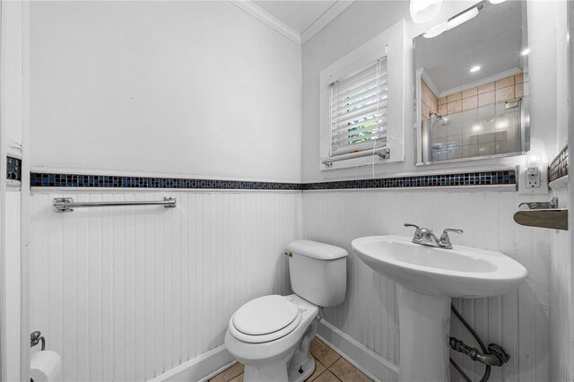 bathroom with tile patterned flooring, sink, wood walls, crown molding, and toilet