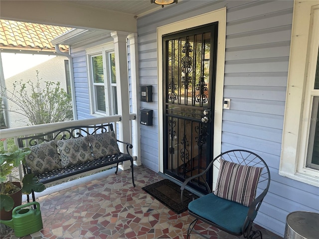 property entrance with covered porch and a tile roof