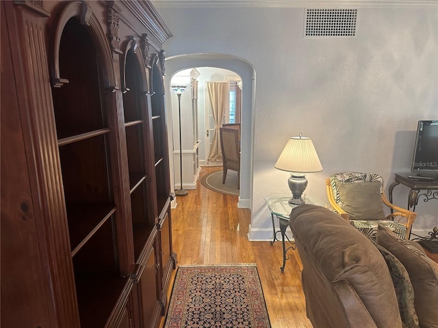 corridor with visible vents, arched walkways, light wood-style floors, and baseboards