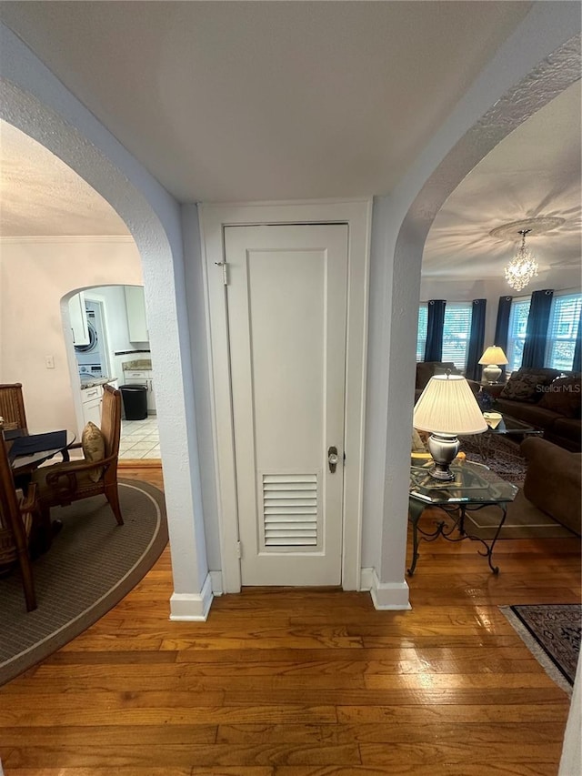 corridor with arched walkways, visible vents, an inviting chandelier, and hardwood / wood-style floors