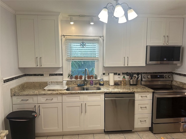 kitchen with a sink, light stone countertops, appliances with stainless steel finishes, and white cabinetry