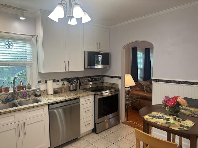 kitchen with a sink, crown molding, wainscoting, and stainless steel appliances