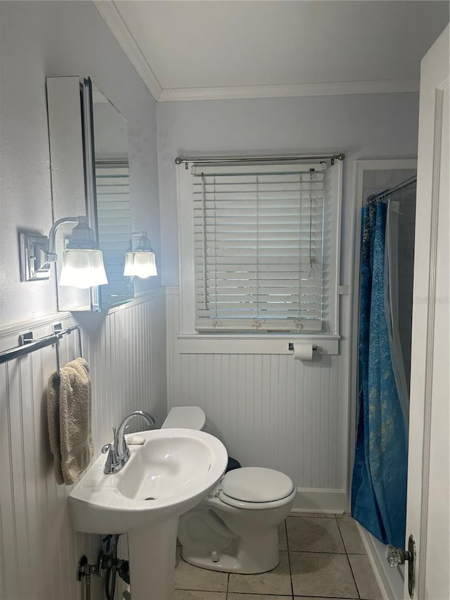 full bathroom with a wainscoted wall, toilet, a shower with shower curtain, ornamental molding, and tile patterned floors