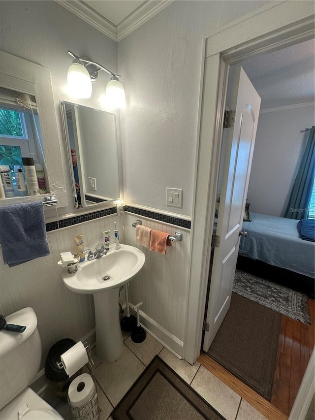 bathroom with tile patterned floors, wainscoting, ensuite bathroom, and ornamental molding