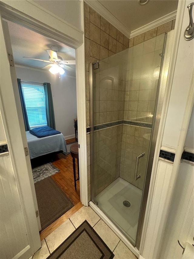 ensuite bathroom with a stall shower, ornamental molding, a ceiling fan, and tile patterned flooring