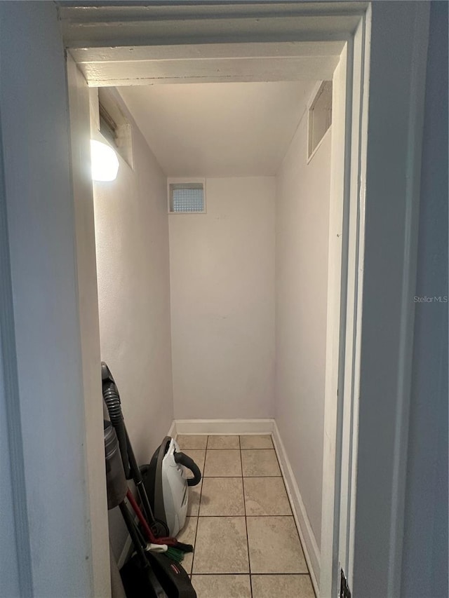 hallway featuring visible vents, baseboards, and tile patterned flooring