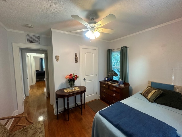 bedroom featuring visible vents, ceiling fan, ornamental molding, dark wood-style floors, and a textured ceiling