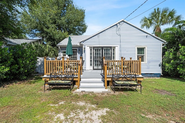 rear view of property featuring a yard, metal roof, and a wooden deck