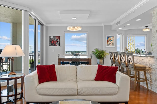 living room with a notable chandelier, crown molding, and hardwood / wood-style flooring