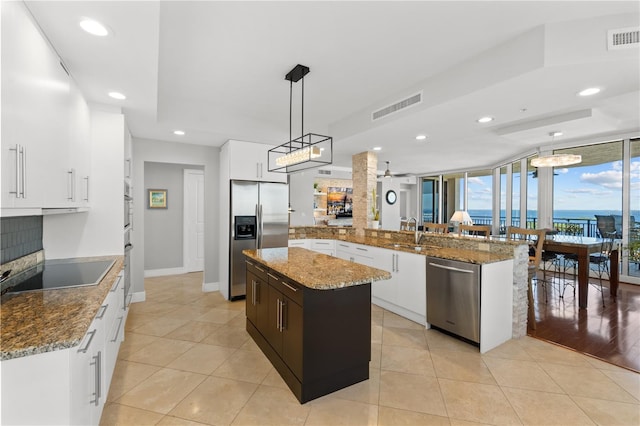 kitchen featuring a center island, kitchen peninsula, stainless steel appliances, pendant lighting, and light hardwood / wood-style flooring