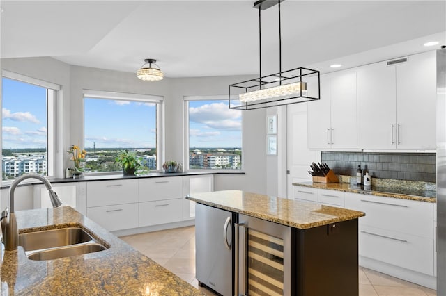 kitchen with wine cooler, an island with sink, a healthy amount of sunlight, and white cabinets