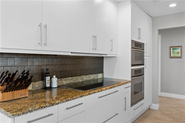 kitchen featuring black electric stovetop, dark stone countertops, oven, and white cabinets