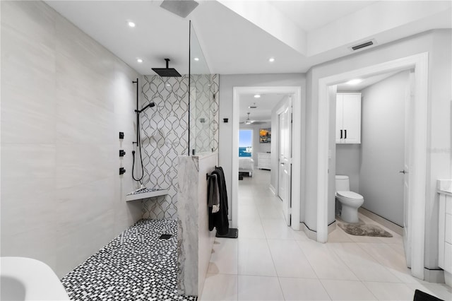 bathroom featuring tile walls, tiled shower, toilet, and tile patterned floors