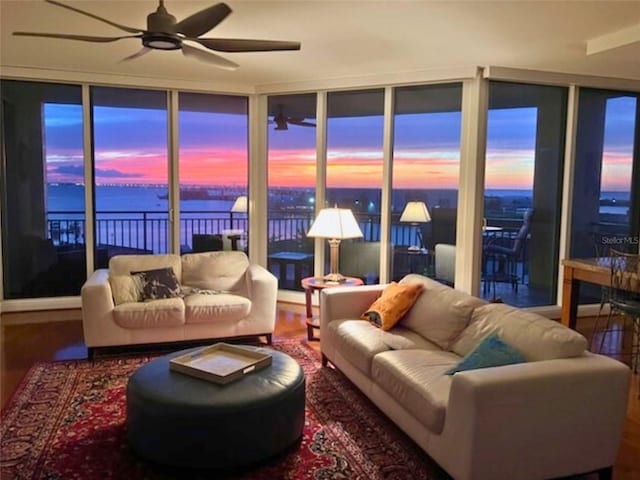 living room featuring a wall of windows, hardwood / wood-style floors, a water view, and ceiling fan