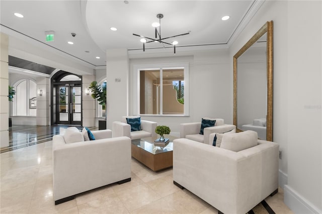 living room featuring french doors, ornamental molding, and a notable chandelier