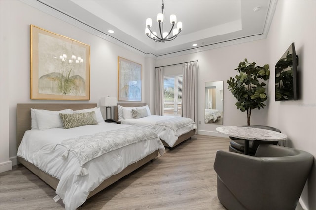 bedroom featuring crown molding, a notable chandelier, light wood-type flooring, and a raised ceiling