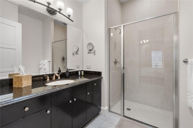 bathroom with a shower with door, vanity, and tile patterned floors